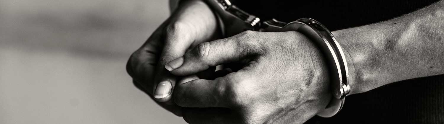 black and white photo of man's hands in handcuffs